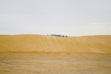 Group of off-roadster cars on sand hill. Car tour of the Sahara desert. Tunisia.