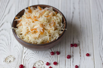sauerkraut with cranberries in a clay plate on a wooden table