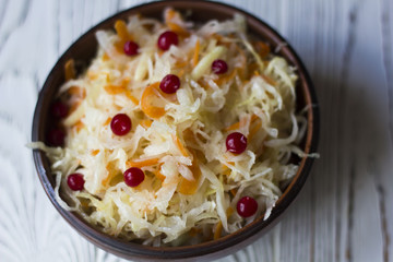 sauerkraut with cranberries in a clay plate on a wooden table