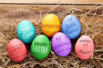 Easter eggs with decoration and text on straw and wood