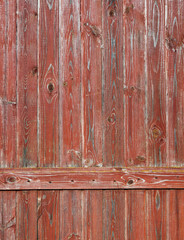 A fragment of a wooden old aged  village fence was once painted with oil red paint.