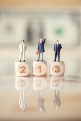 Miniature people: businessman standing on wooden podium with dollar bank note blur background...