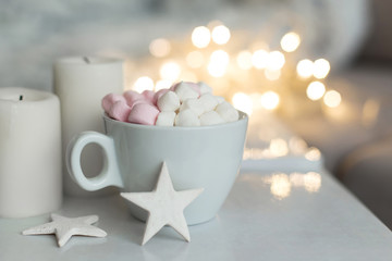 Cup of hot chocolate and marshmallow in the background of Christmas decorations.