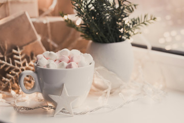 Cup of hot chocolate and marshmallow in the background of Christmas decorations.