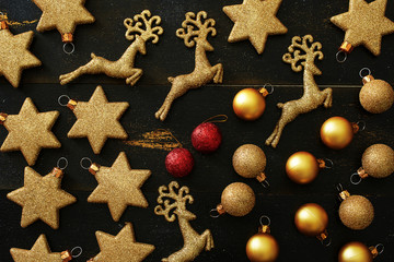 Top view of golden and red Christmas decorations (balls, stars, deers) over black background 