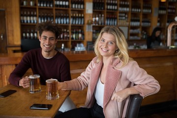 Happy couple having glass of beer in bar