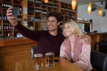 Couple taking selfie with mobile phone in bar