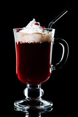 Hot cocktail with whipped cream and lemon juice in a glass on dark background