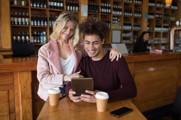 Couple using digital tablet in bar