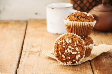 Carrot cake muffins with nuts, raisins and oats on a wooden background. Rustic style.
