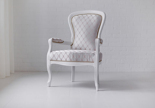 Elegant white armchair on white wall background