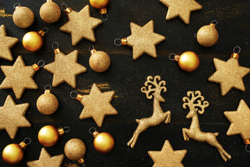 Top view of golden Christmas decorations (balls, stars, deers) over black background