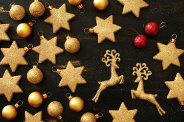 Golden and red xmas toys over black background. Flat lay