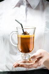 The unidentified waiter holding a glass with hot buttered Becherovka cocktail