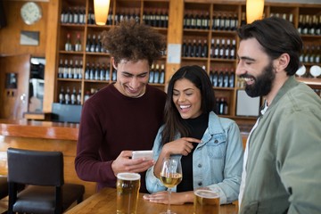Friends looking their photos on mobile phone in bar