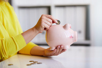 Obraz na płótnie Canvas Close up of woman putting coin into piggy bank