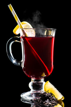 Hot cocktail with lemon, cherry juice and Assam tea on dark background