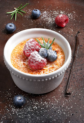 Creme brulee with berries and vanilla stick, closeup
