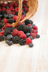 different berries in a basket on a wooden table
