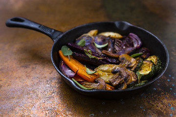 Baked vegetables with herbs in a cast iron pan.
