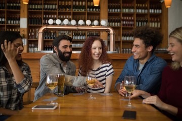 Friends interacting while having glass of beer