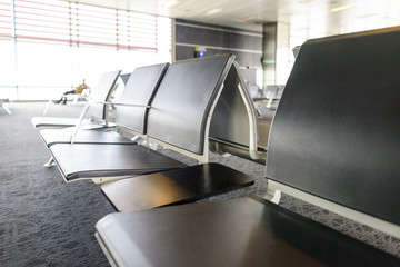 Empty chairs in the departure hall at airport , railway station with blured silhouette of a traveler near window. Travel and transportation concepts