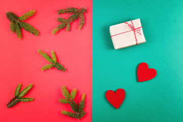 Fir tree branch and small gifts on red and green background. Top view, flat lay. Christmas composition