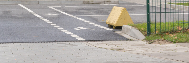Gelbe Beton Bar­ri­e­re auf einem Parkplatz 