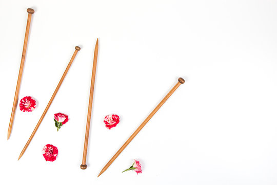 Wooden knitting needles and fresh roses on white background