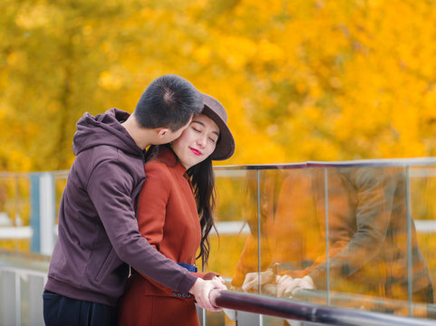 Chinese young man kissing his girlfriend and standing together with emotional expression, a little bit shy, lover concept.