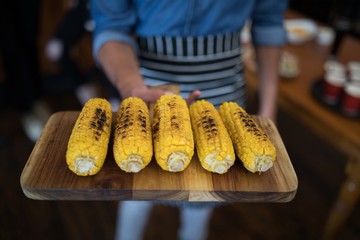Waiter holding tray of baby corn in bar