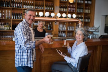 Two friends having glass of beer at counter in restaurant