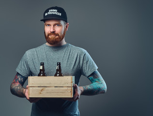 A man holds a wooden box with beer bottles.