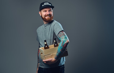 A man holds a wooden box with beer bottles.