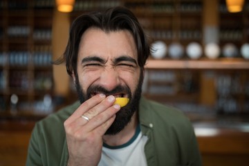Man biting into lemon wedge after having tequila shot