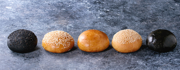 Set of different whole homemade black, white, with and without sesame seeds burger buns in row over...