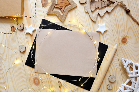 Christmas background kraft sheet of paper with place for your text and white christmas star and garland on wooden background. Flat lay, top view photo mockup