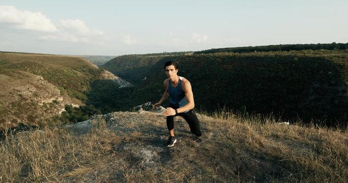 Healthy, young, handsome, attractive, white man warming up for a morning run on a mountain peak. Red Epic