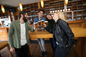 Friends toasting glass of beer in bar