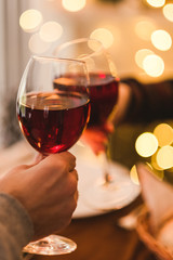 Hands cheering with glasses of wine. Dinner date for two. Romantic lights background. Love and food concept