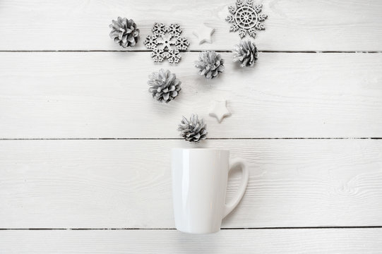 Mockup white mug with christmas cones and stars, on a white wooden background. Flat lay, top view photo mock up