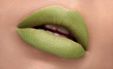 Cosmetics, makeup. Green matte fashion lipstick on open lips. Closeup beautiful female mouth with sexy lip make-up. Part of face. Plump lips