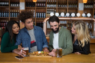 Group of friends having glass of beer and mexican food in bar
