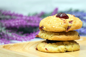 Cranberry cookies on wooden plate with blurred pink and violet flowers background