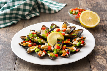 Steamed mussels with peppers and onion on wooden table