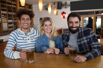 Friends having glass of drinks at counter in restaurant
