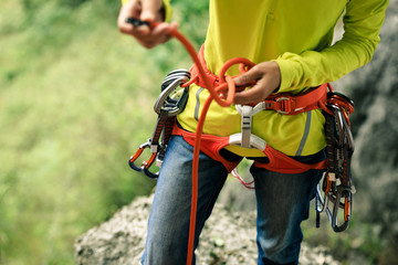 Сlimber wearing safety harness making a eight rope knot