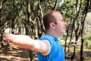 Handsome young man is doing stretching exercises in forest. Sportsman wearing sportswear in landscape nature outdoors. Pretty guy, active, cross fit, healthy lifestyle, fitness relax people concept.