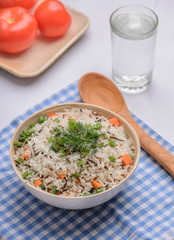 boiled mix rice in a white bowl on the white table with a wood spoon