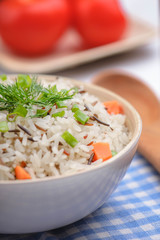 boiled mix rice in a white bowl on the white table with a wood spoon